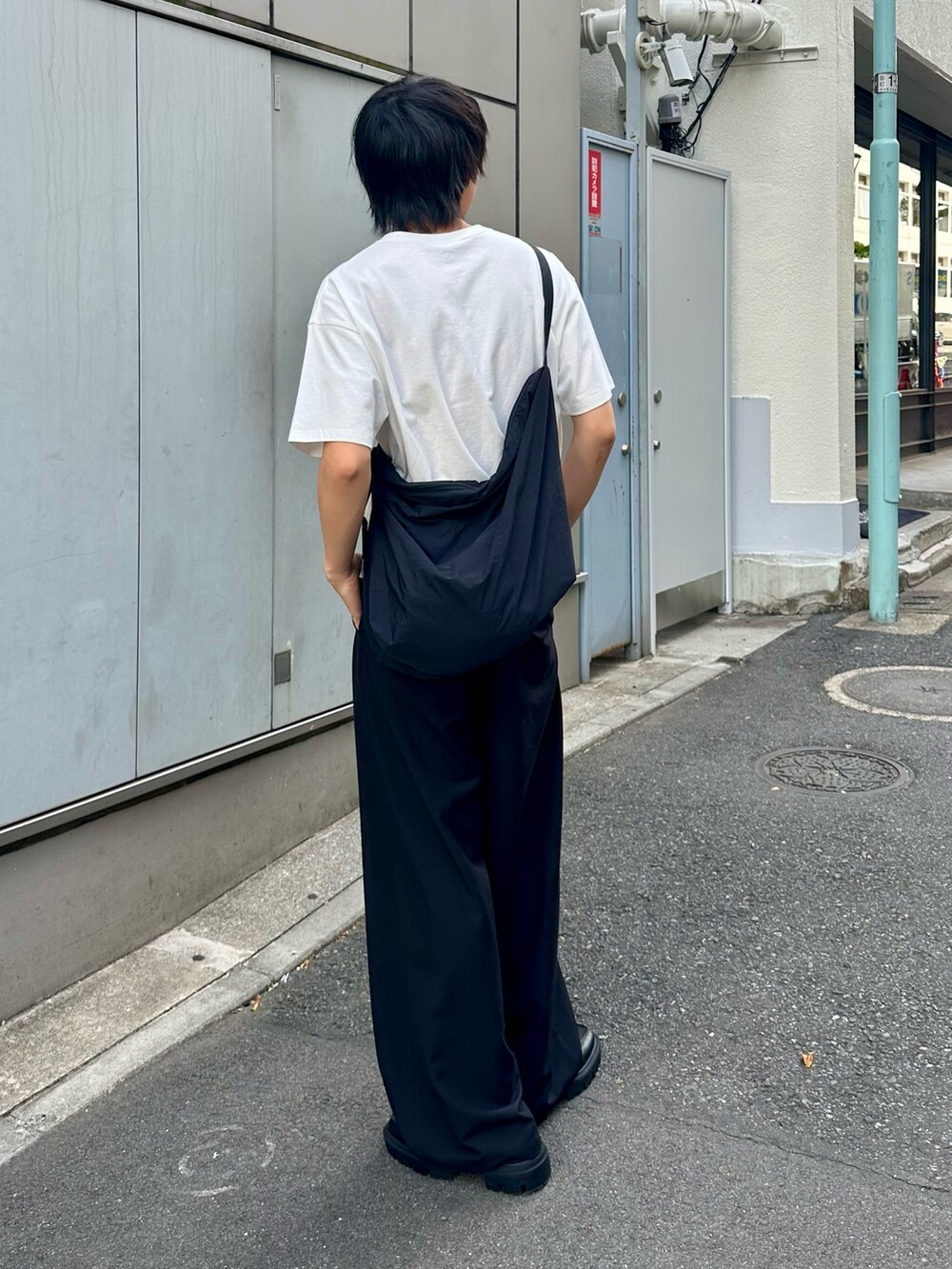 ブラック系のスラックス、ブラック系のショルダーバッグ、ホワイト系のTシャツ/カットソーを着用したメンズの春コーディネートの4枚目の写真