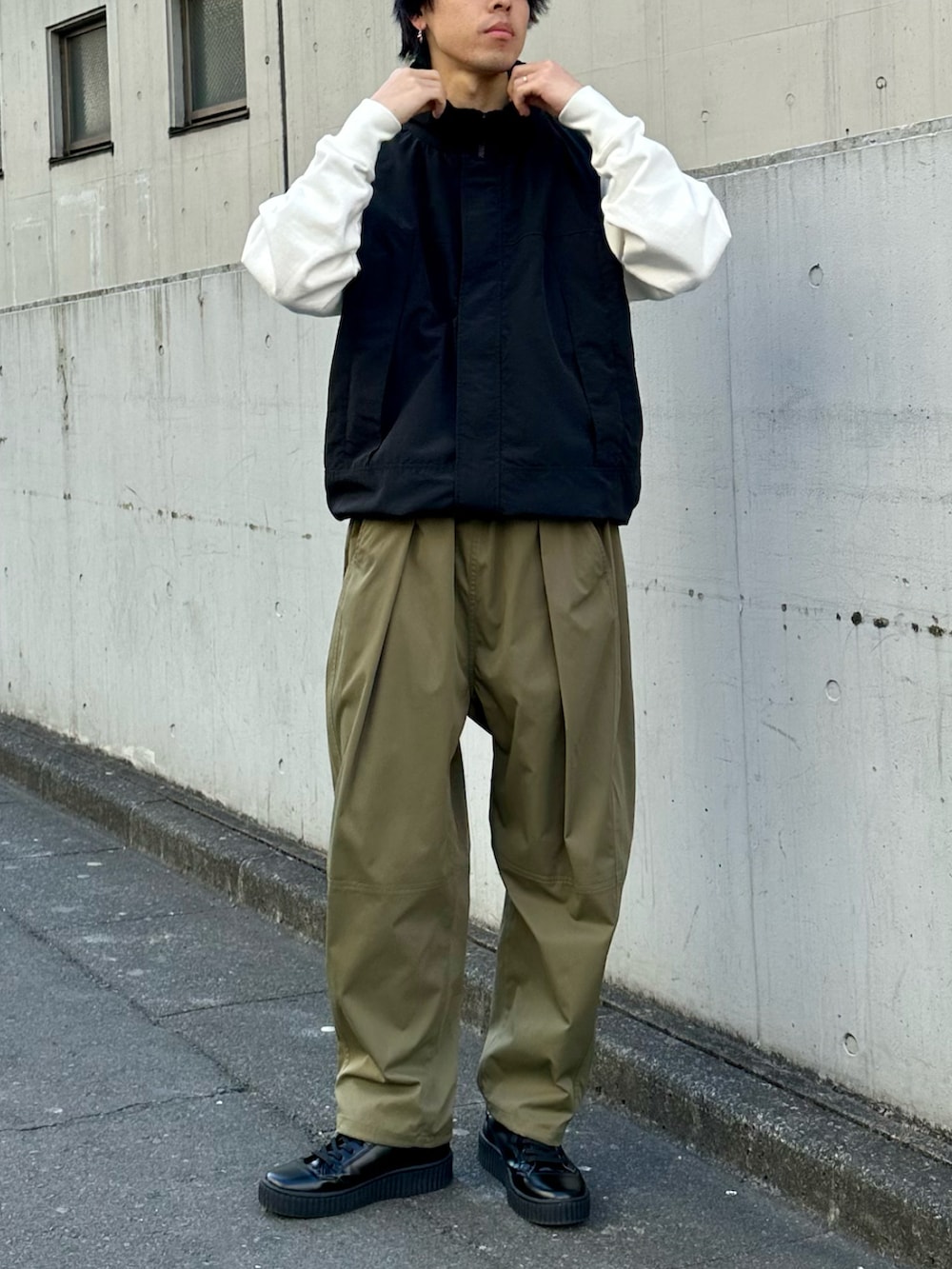 ブラック系のベスト、グリーン系のその他パンツ、ホワイト系のスウェットを着用したメンズの春コーディネートの3枚目の写真