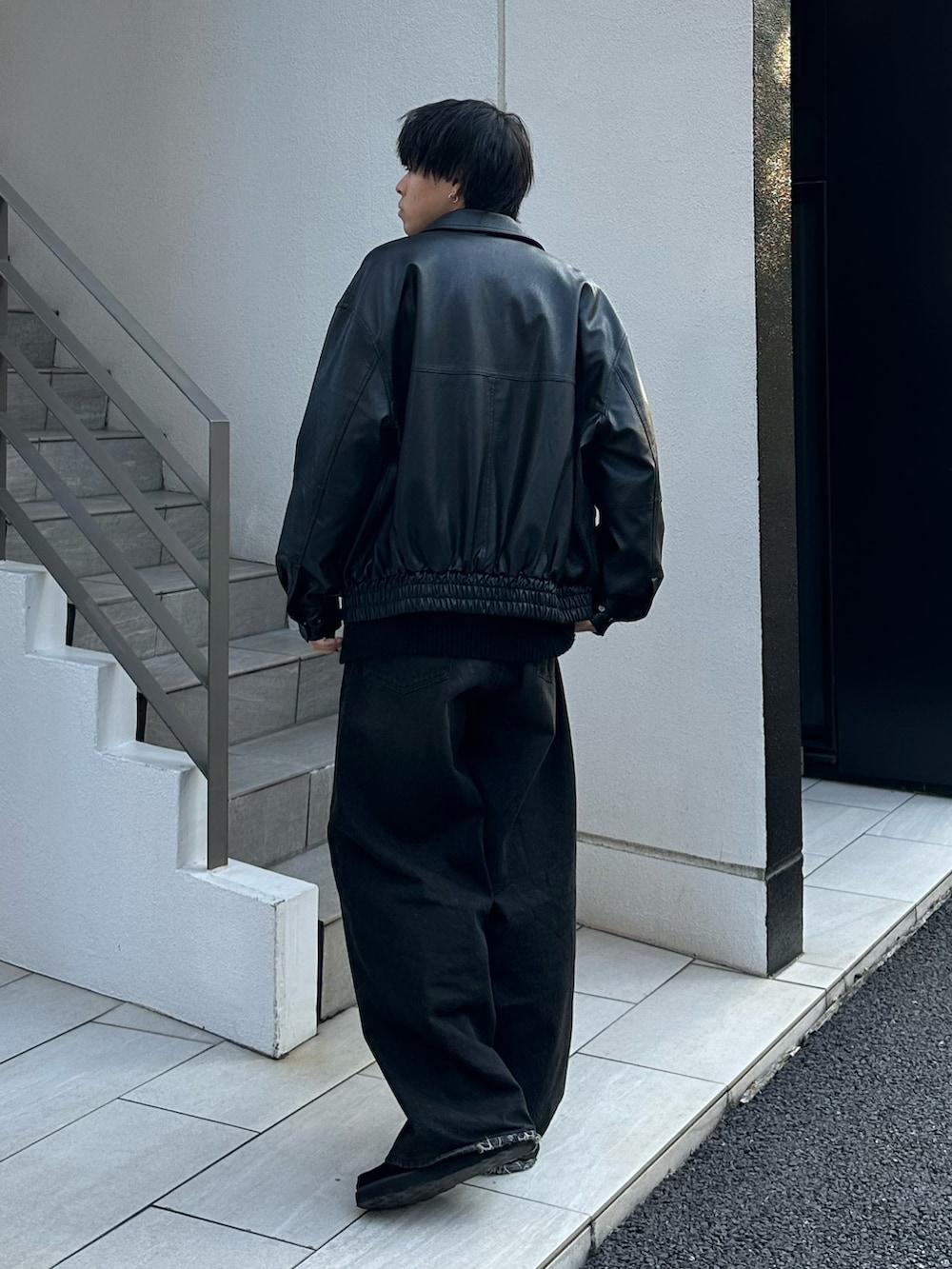 ブラック系のブルゾン、グレー系のニット/セーター、ブラック系のデニムパンツを着用したメンズの秋コーディネートの4枚目の写真
