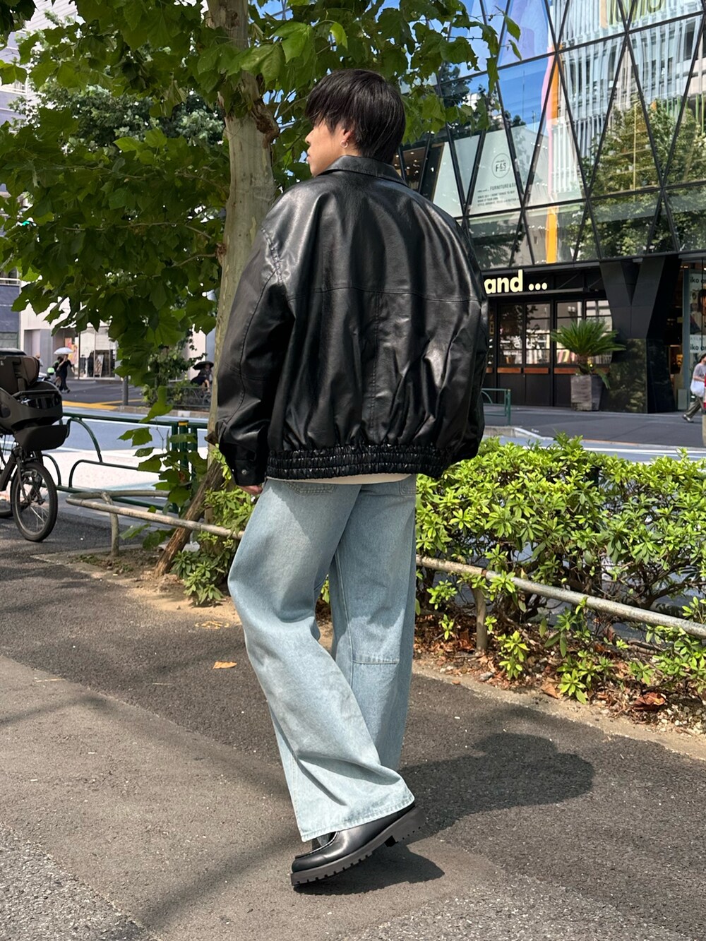 ブラック系のブルゾン、ホワイト系のスウェット、ブルー系のデニムパンツを着用したメンズの秋コーディネートの3枚目の写真