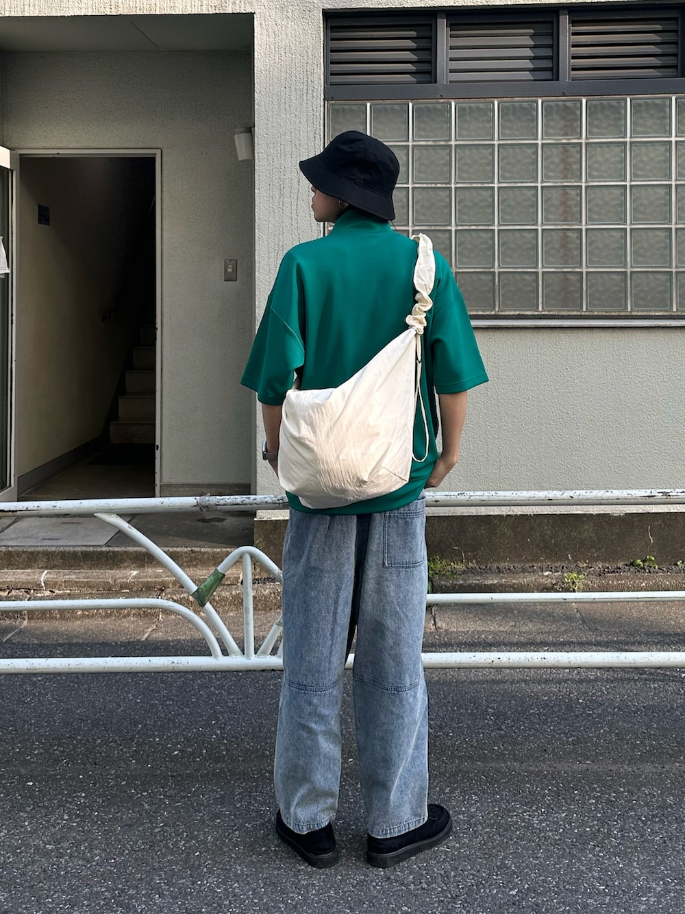 グリーン系のTシャツ/カットソー、ブルー系のデニムパンツ、ホワイト系のショルダーバッグを着用したメンズの春コーディネートの2枚目の写真