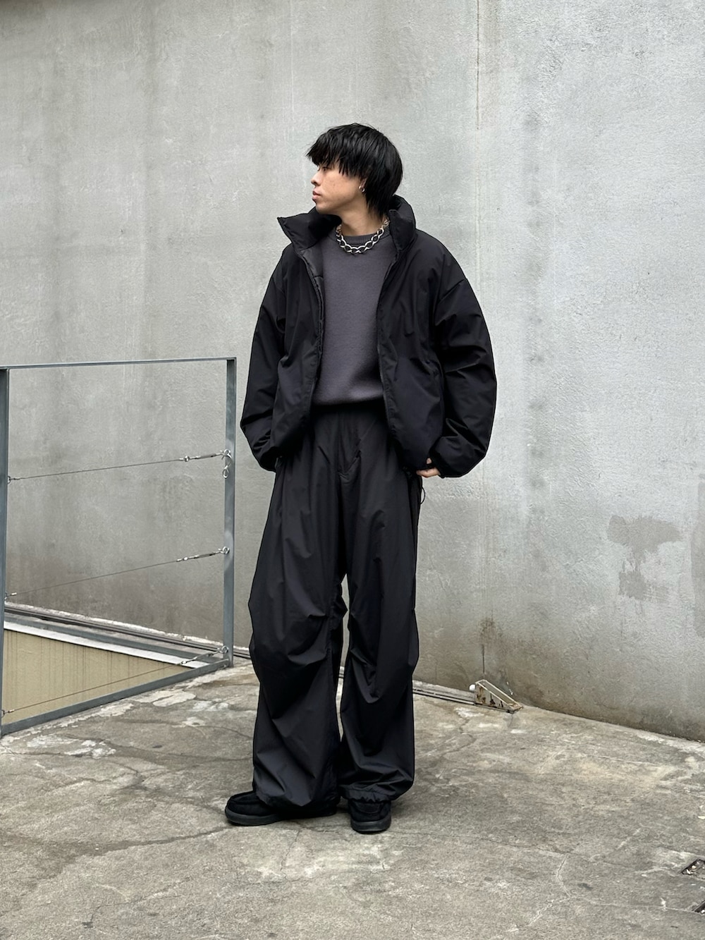 ブラック系のダウンジャケット/コート、グレー系のニット/セーター、ブラック系のその他パンツを着用したメンズの冬コーディネートの2枚目の写真