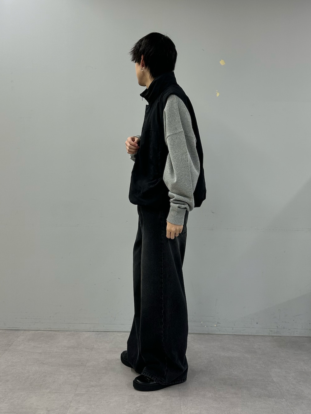 ブラック系のベスト、グレー系のスウェット、ブラック系のデニムパンツを着用したメンズの冬コーディネートの2枚目の写真