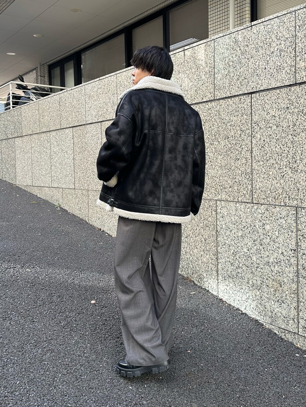 ブラック系のムートンコート、ブラック系のTシャツ/カットソー、グレー系のスラックスを着用したメンズの冬コーディネートの3枚目の写真