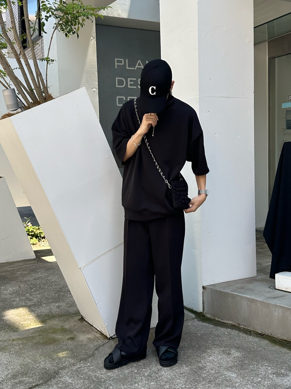 ブラック系のスラックス、ブラック系のTシャツ/カットソー、ブラック系のショルダーバッグを着用したメンズの夏コーディネートの5枚目の写真