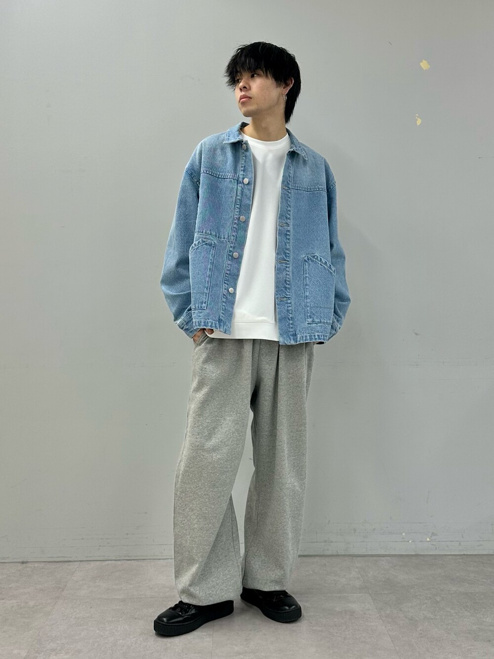 ブルー系のデニムジャケット、グレー系のスウェットパンツ、ブラック系のスニーカーを着用したメンズの冬コーディネートの2枚目の写真