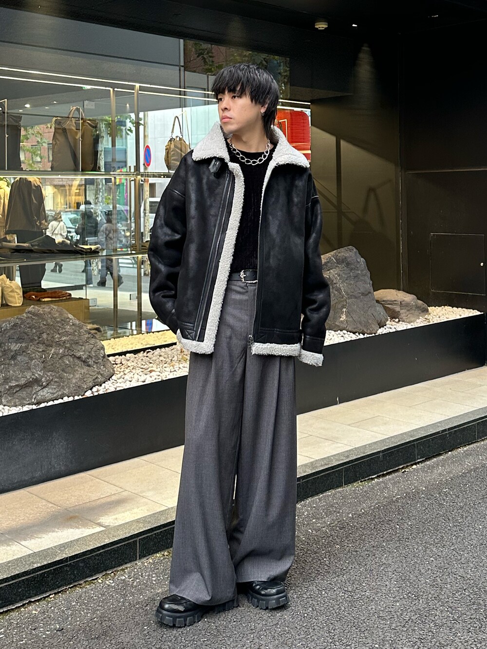 ブラック系のムートンコート、ブラック系のTシャツ/カットソー、グレー系のスラックスを着用したメンズの冬コーディネートの4枚目の写真