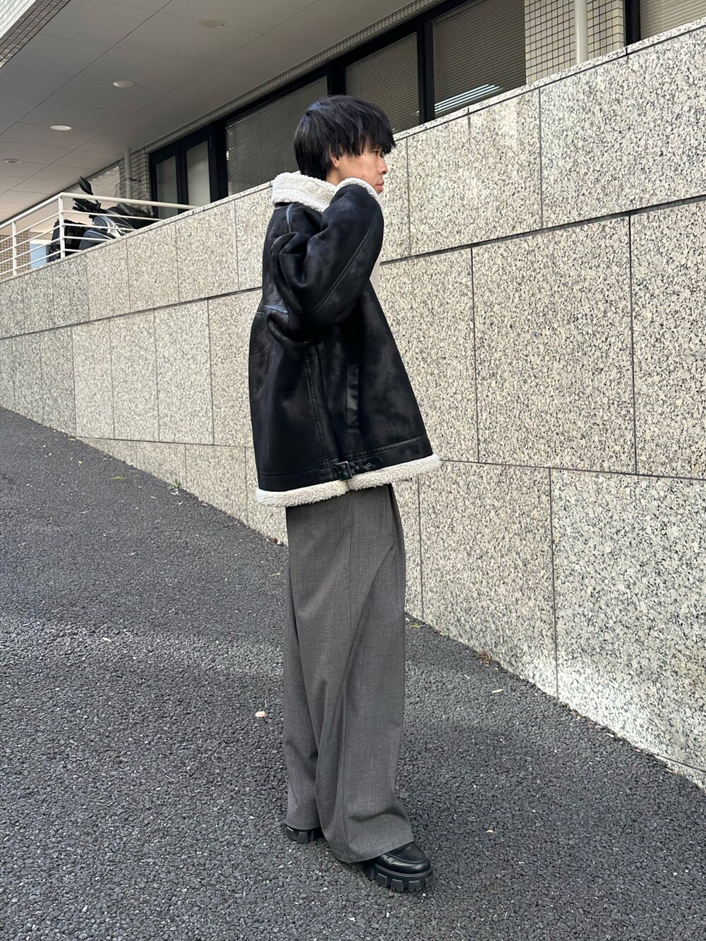 ブラック系のムートンコート、ブラック系のTシャツ/カットソー、グレー系のスラックスを着用したメンズの冬コーディネートの4枚目の写真