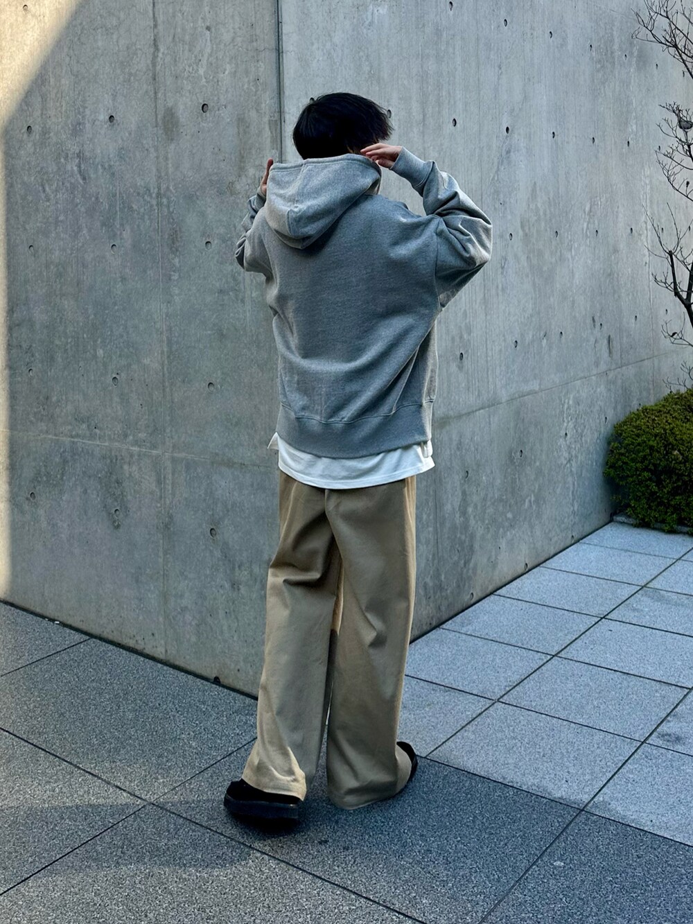 グレー系のパーカー、ベージュ系のスラックスを着用したメンズの冬コーディネートの3枚目の写真