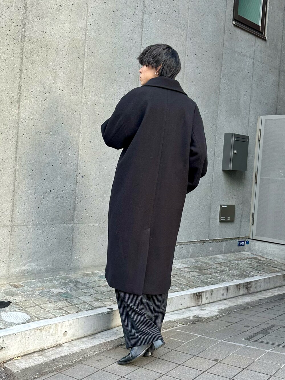 ブラック系のその他アウター、ブラック系のニット/セーター、ブラック系のスラックスを着用したメンズの冬コーディネートの3枚目の写真