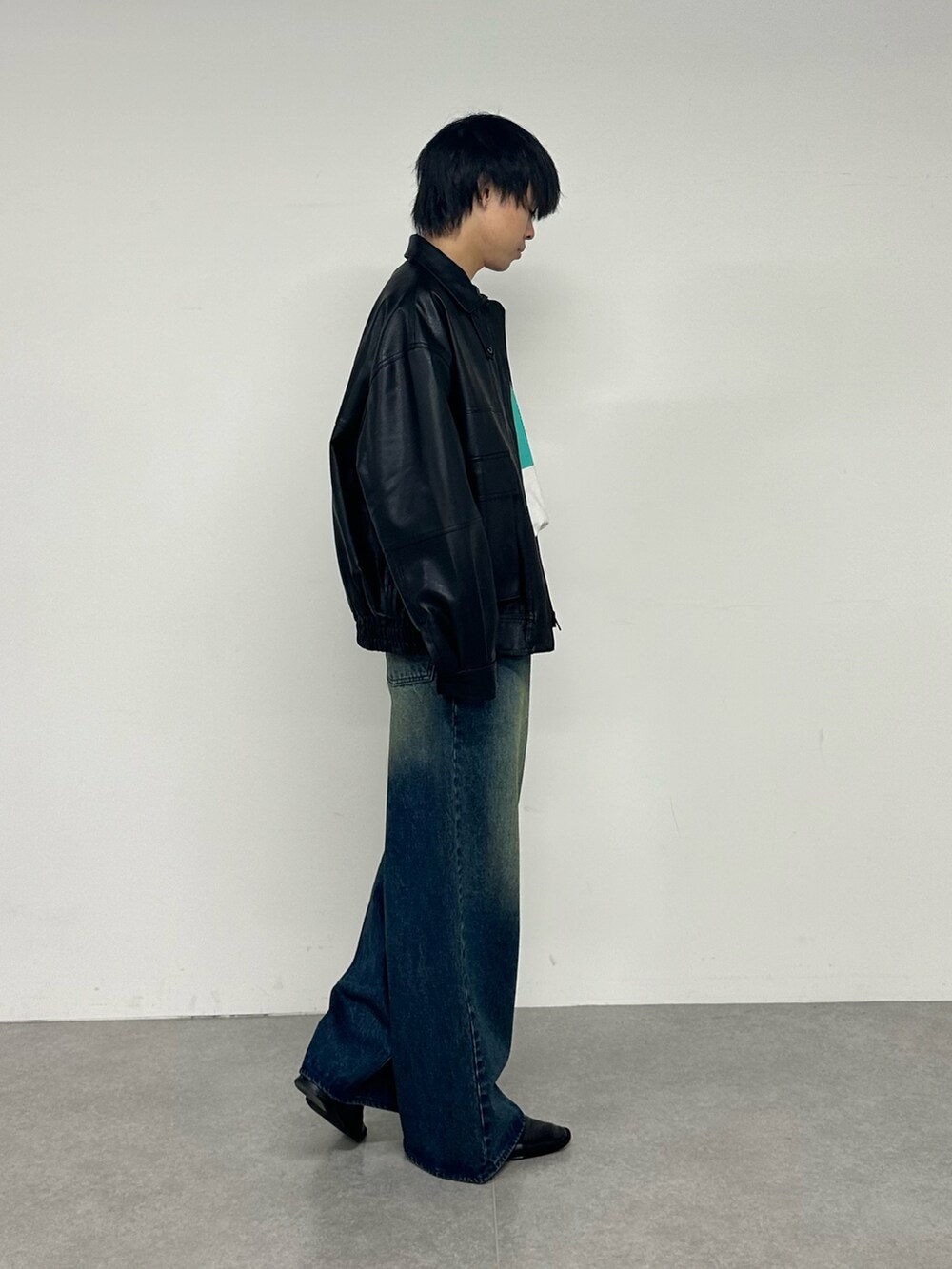 ブラック系のブルゾン、ホワイト系のTシャツ/カットソー、ブルー系のデニムパンツを着用したメンズの夏コーディネートの4枚目の写真