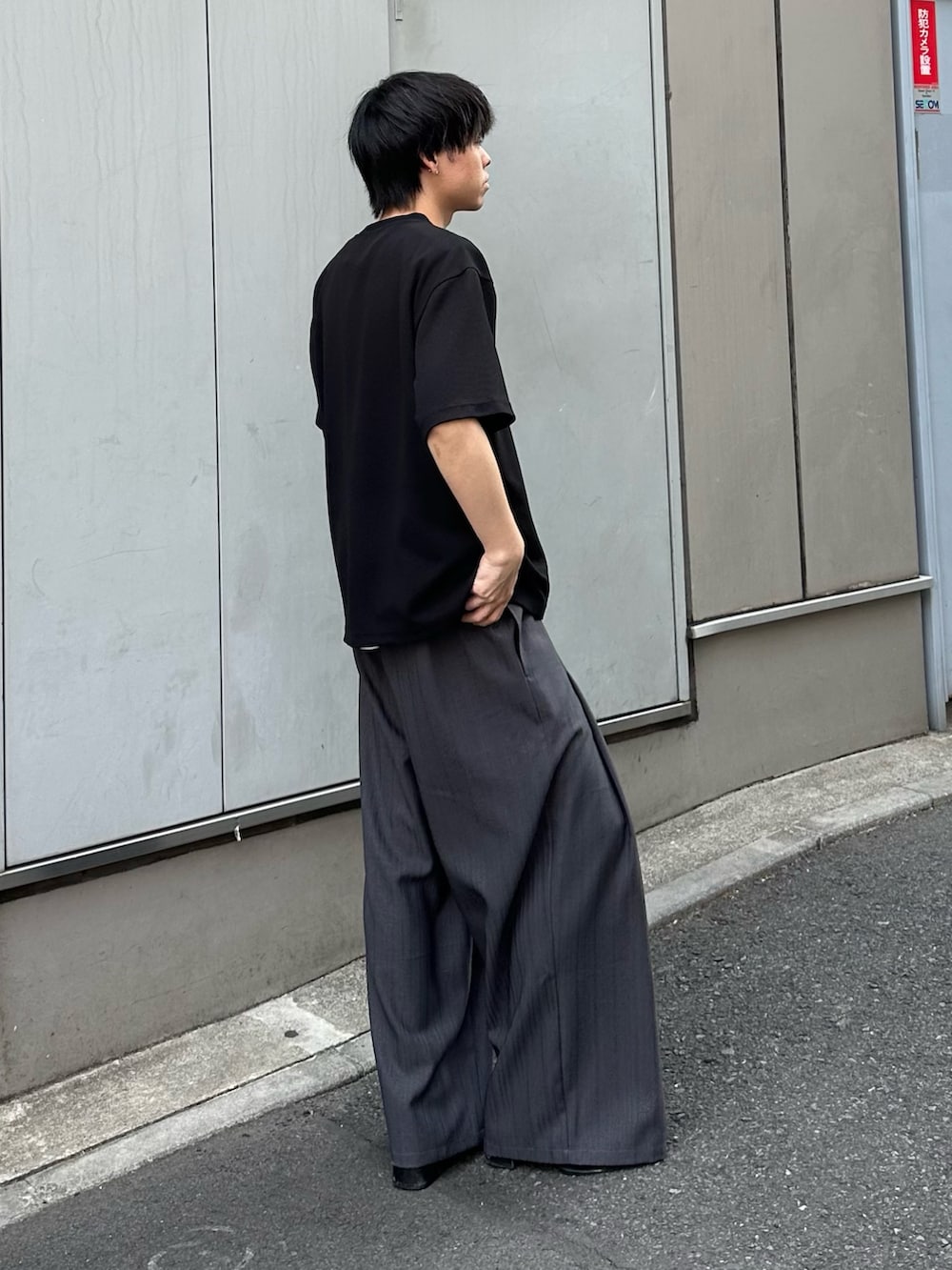 ブラック系のTシャツ/カットソー、グレー系のスラックスを着用したメンズの春コーディネートの4枚目の写真