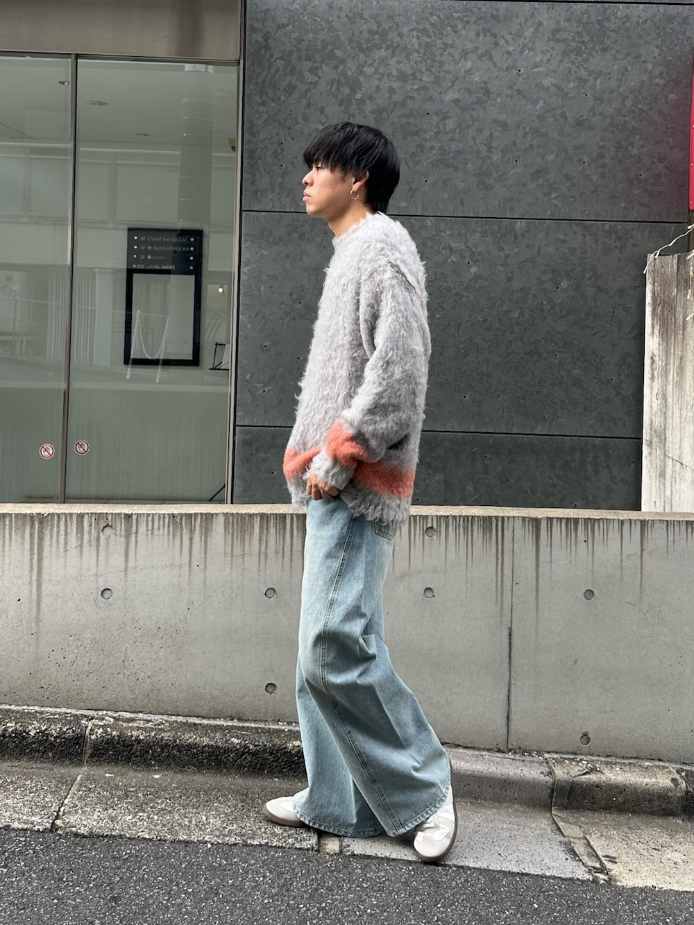 グレー系のニット/セーター、ブルー系のデニムパンツ、ホワイト系のスニーカーを着用したメンズの秋コーディネートの3枚目の写真