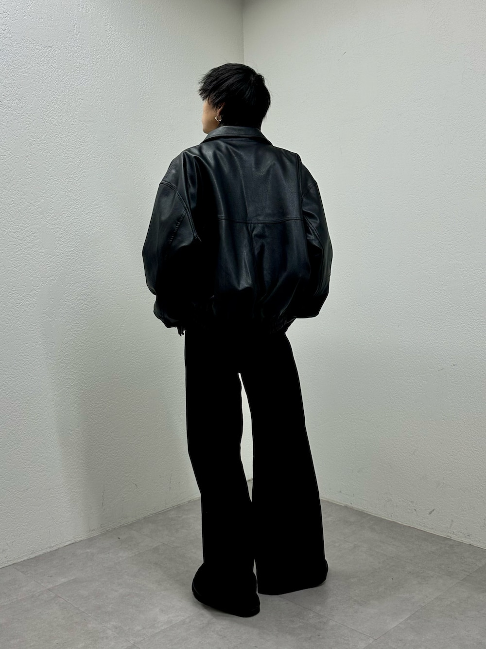 ブラック系のブルゾン、グレー系のTシャツ/カットソー、ブラック系のスラックスを着用したメンズの冬コーディネートの2枚目の写真