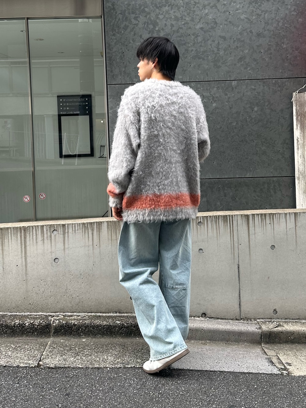 グレー系のニット/セーター、ブルー系のデニムパンツ、ホワイト系のスニーカーを着用したメンズの秋コーディネートの4枚目の写真