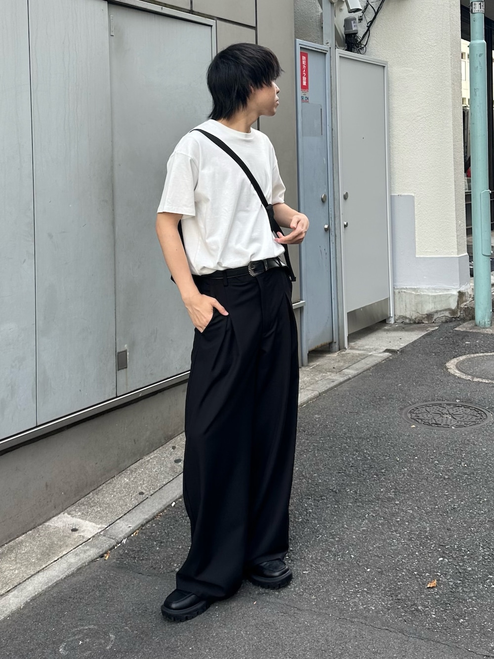 ブラック系のスラックス、ブラック系のショルダーバッグ、ホワイト系のTシャツ/カットソーを着用したメンズの春コーディネートの2枚目の写真