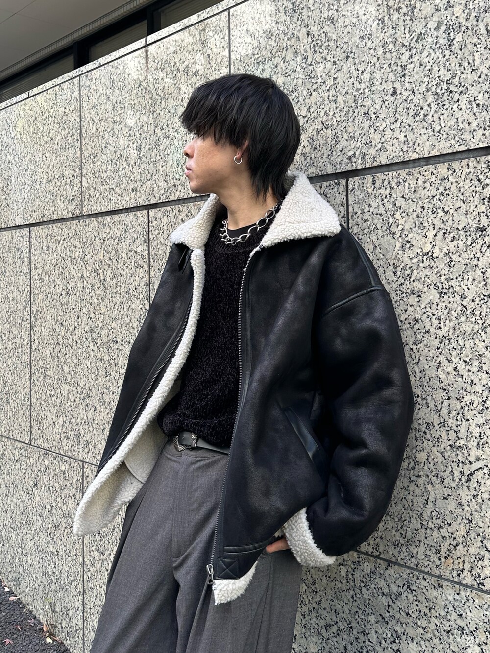 ブラック系のムートンコート、ブラック系のTシャツ/カットソー、グレー系のスラックスを着用したメンズの冬コーディネートの5枚目の写真