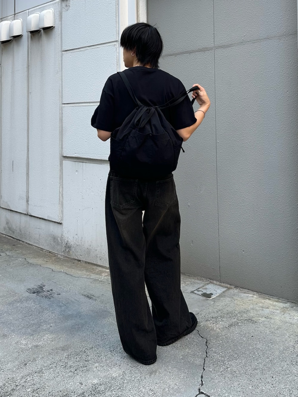ブラック系のバックパック/リュック、ブラック系のデニムパンツ、ブラック系のTシャツ/カットソーを着用したメンズの夏コーディネートの3枚目の写真