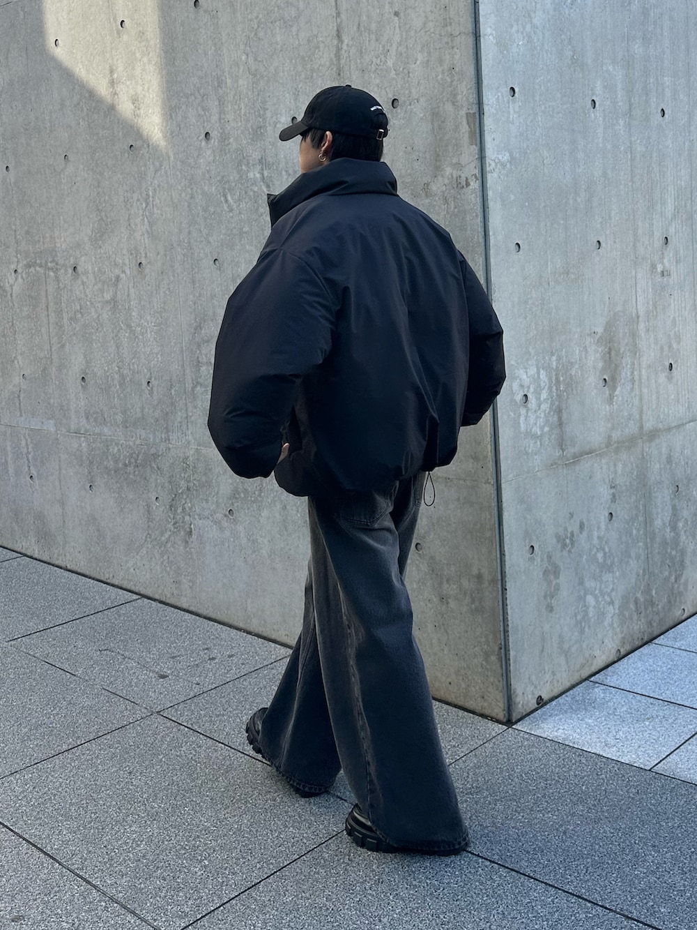 ブラック系のデニムパンツ、ブラック系のダウンジャケット/コート、ブラック系のキャップを着用したメンズの冬コーディネートの4枚目の写真