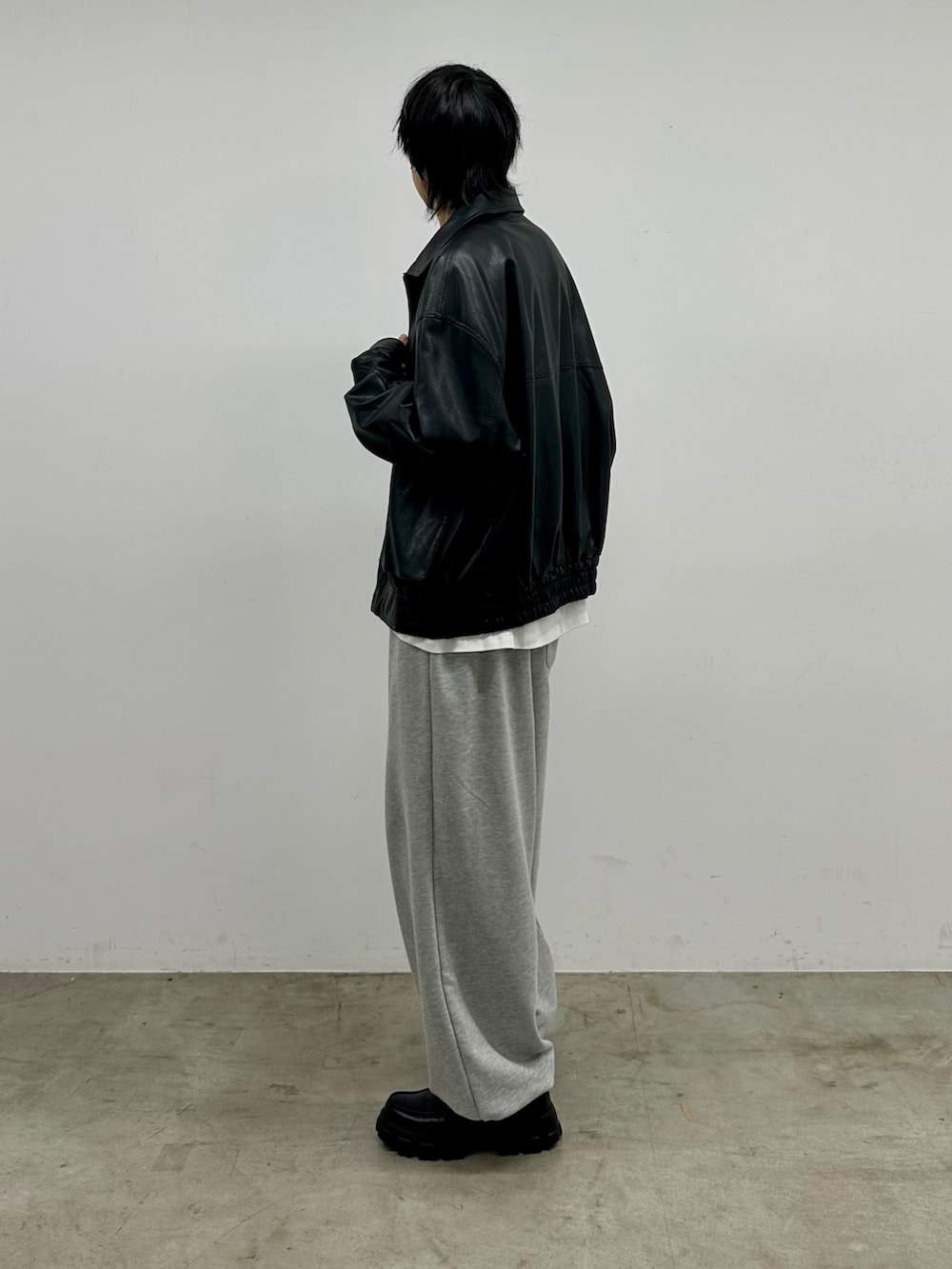 ブラック系のブルゾン、ホワイト系のTシャツ/カットソー、グレー系のスウェットパンツを着用したメンズの秋コーディネートの2枚目の写真