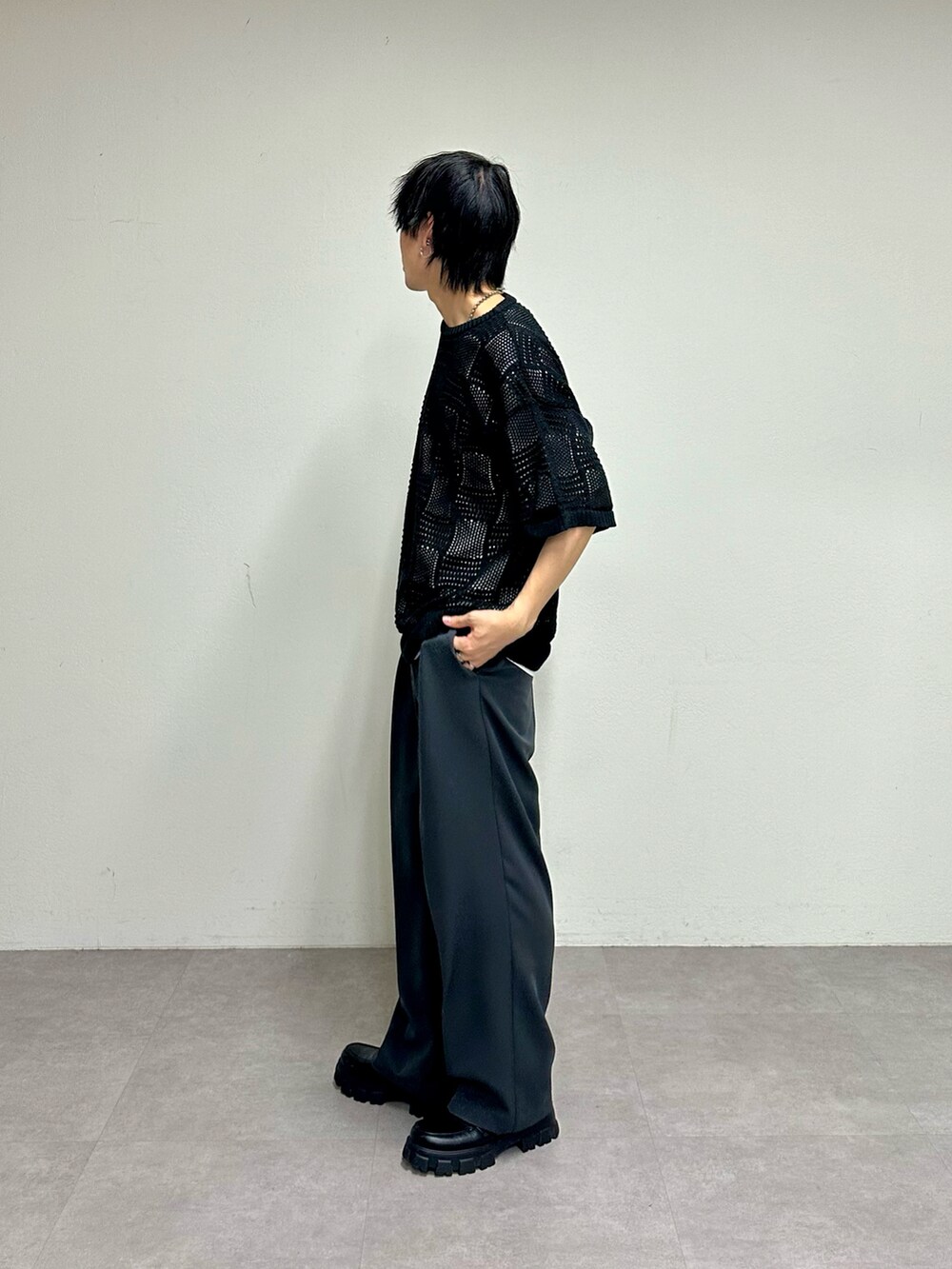 ブラック系のニット/セーター、グレー系のスラックス、ブラック系のショルダーバッグを着用したメンズの春コーディネートの4枚目の写真