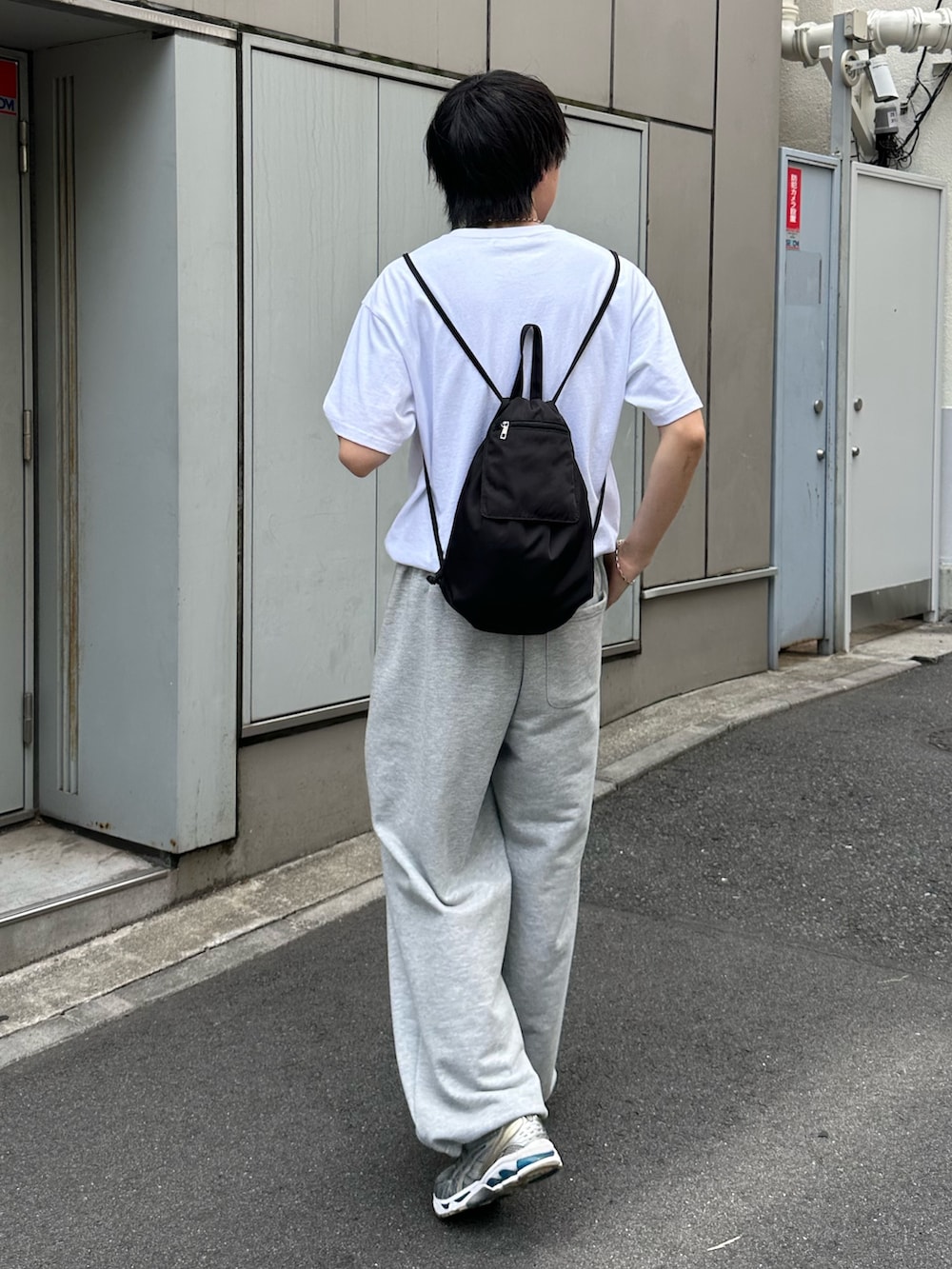 ブラック系のバックパック/リュック、グレー系のスウェットパンツ、ホワイト系のTシャツ/カットソーを着用したメンズの夏コーディネートの2枚目の写真