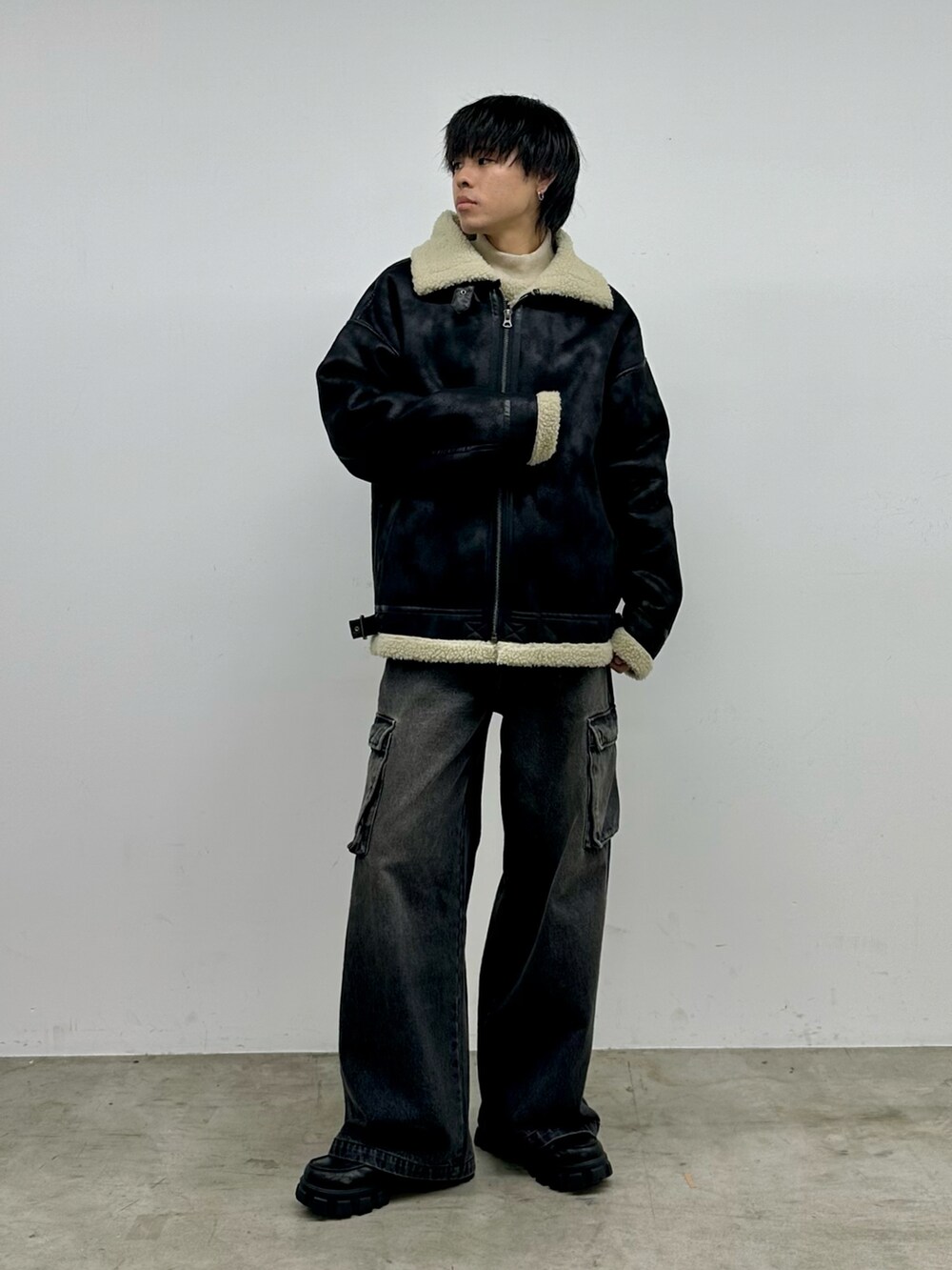 ブラック系のデニムパンツ、ブラック系のムートンコート、ホワイト系のニット/セーターを着用したメンズの秋コーディネートの5枚目の写真