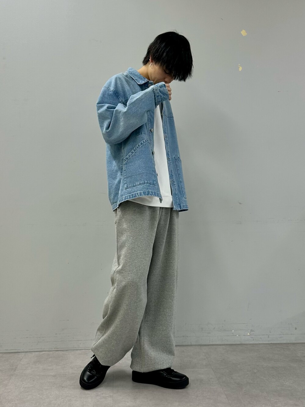 ブルー系のデニムジャケット、グレー系のスウェットパンツ、ブラック系のスニーカーを着用したメンズの冬コーディネートの4枚目の写真