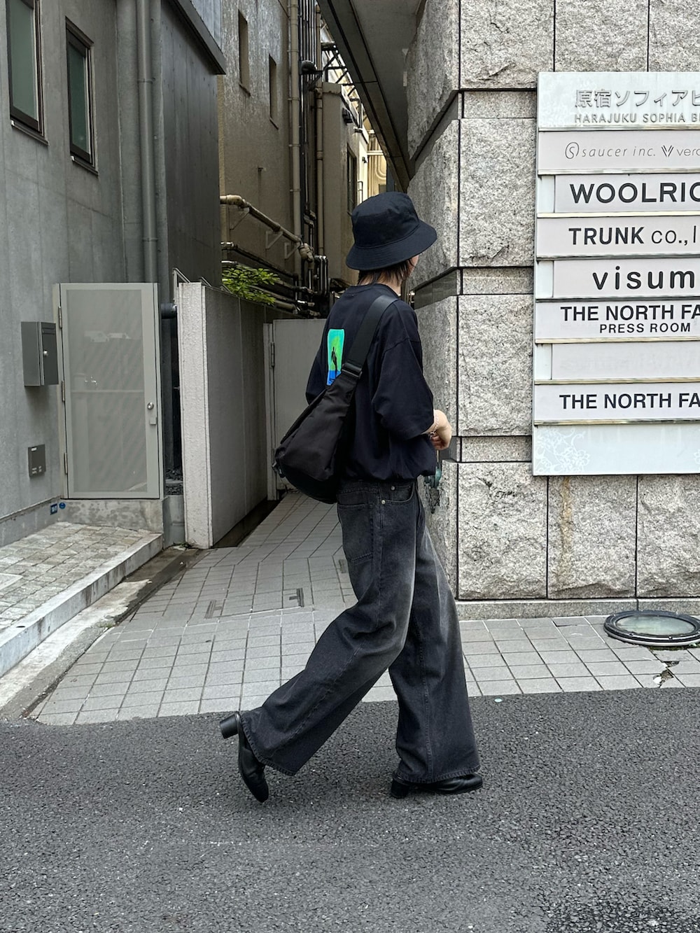 ブラック系のメッセンジャーバッグ、ブラック系のTシャツ/カットソー、ブラック系のデニムパンツを着用したメンズの夏コーディネートの3枚目の写真