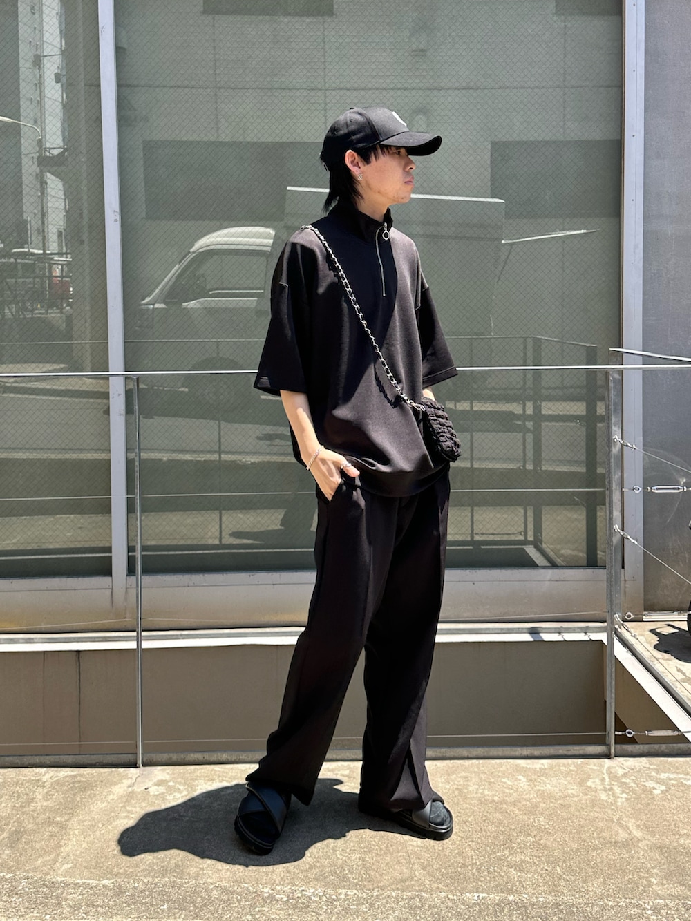 ブラック系のスラックス、ブラック系のTシャツ/カットソー、ブラック系のショルダーバッグを着用したメンズの夏コーディネートの4枚目の写真