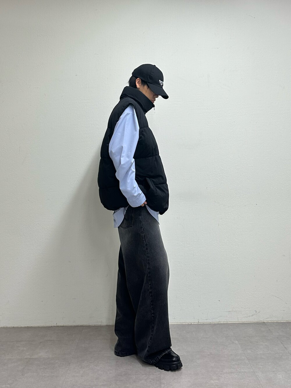 ブラック系のダウンベスト、ブラック系のデニムパンツ、ブルー系のキャップを着用したメンズの夏コーディネートの4枚目の写真