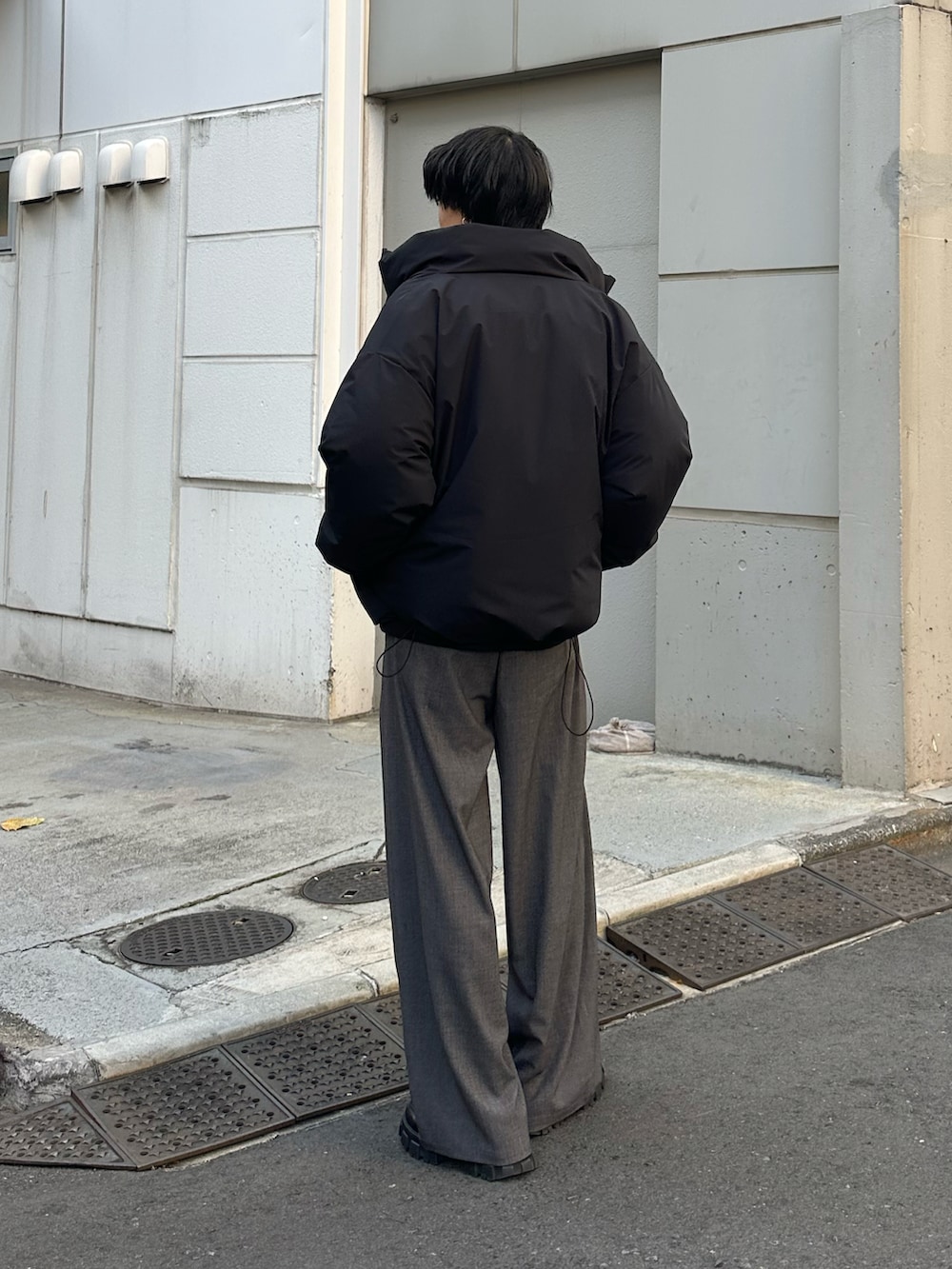 ブラック系のダウンジャケット/コート、グレー系のスラックスを着用したメンズの冬コーディネートの3枚目の写真