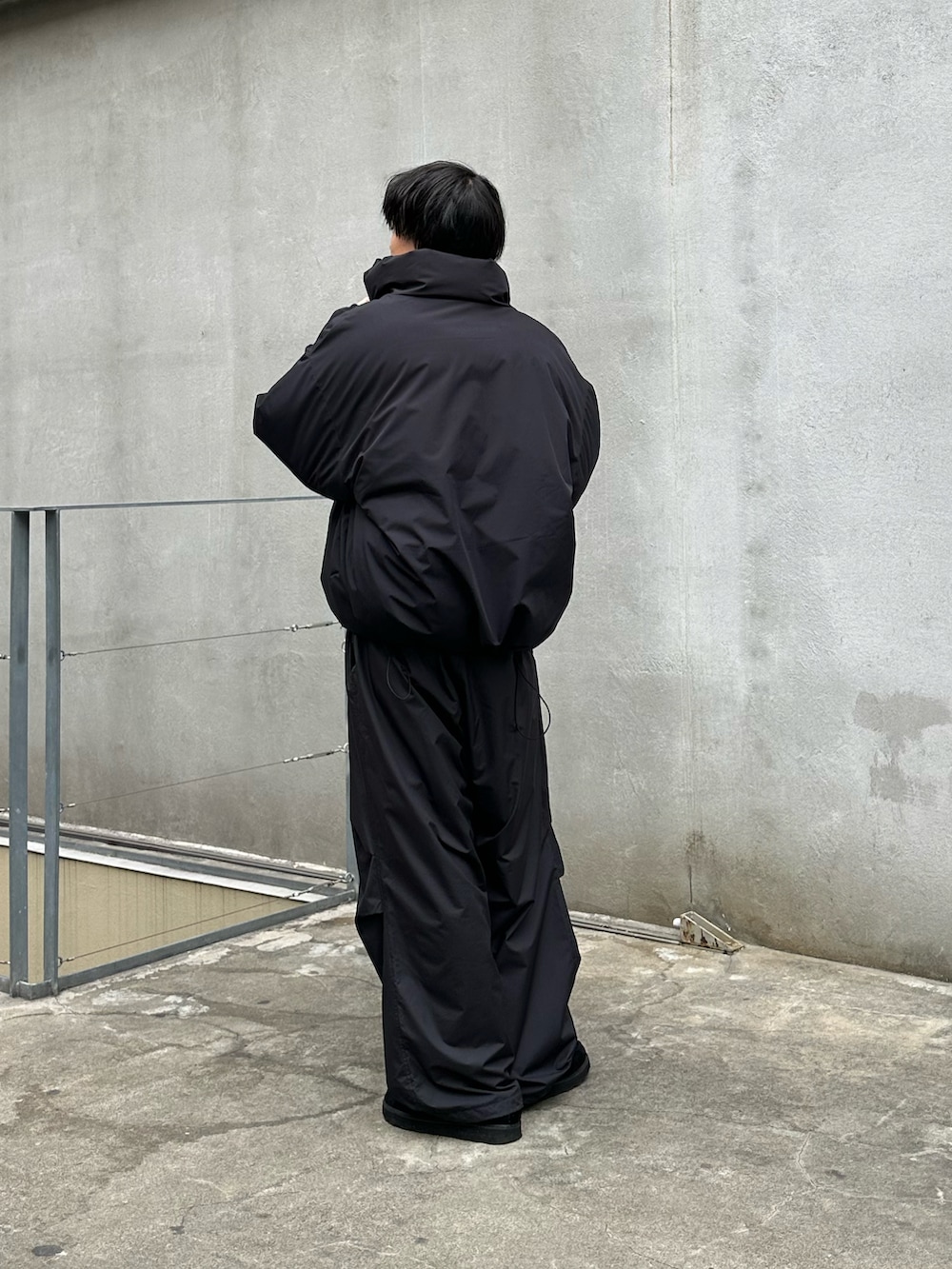 ブラック系のダウンジャケット/コート、グレー系のニット/セーター、ブラック系のその他パンツを着用したメンズの冬コーディネートの3枚目の写真