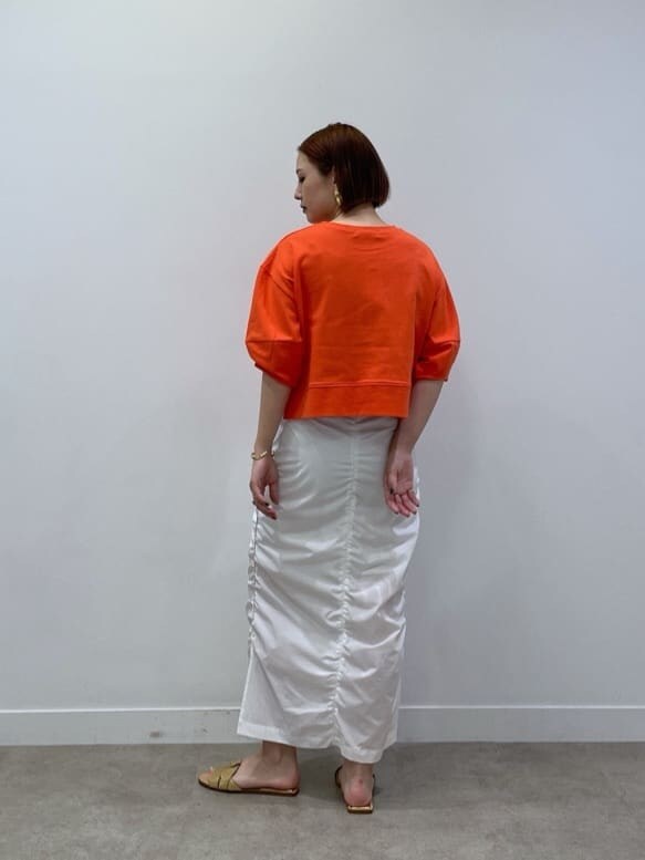 オレンジ系のTシャツ/カットソー、ホワイト系のスカートを着用したレディースの春コーディネートの3枚目の写真