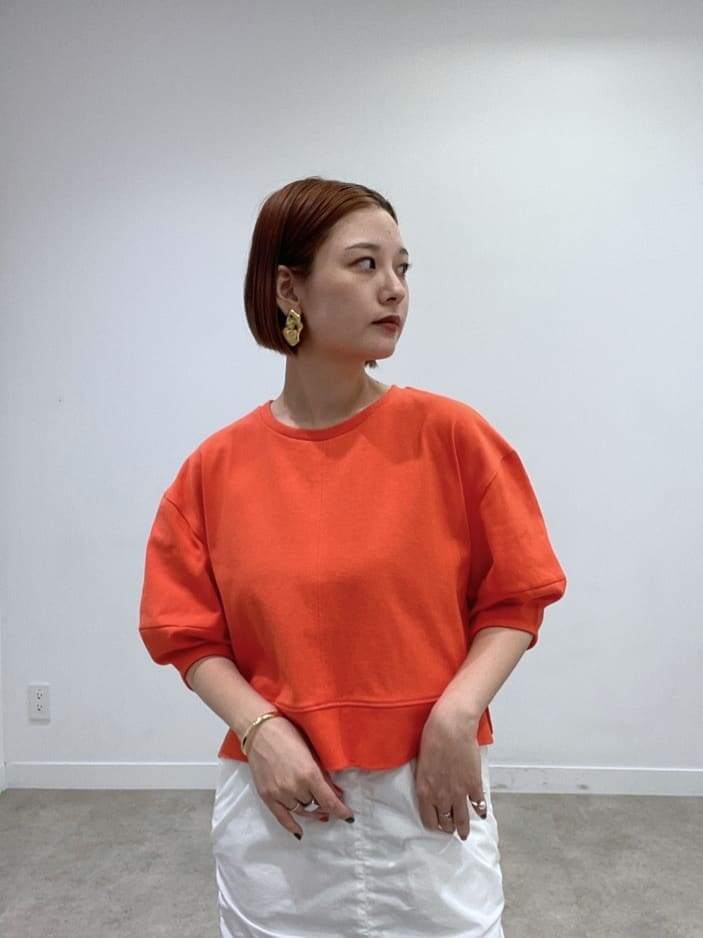 オレンジ系のTシャツ/カットソー、ホワイト系のスカートを着用したレディースの春コーディネートの4枚目の写真