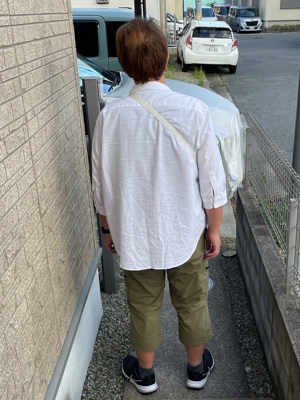 ホワイト系のシャツ/ブラウス、ホワイト系のショルダーバッグ、ブラック系のスニーカーを着用したメンズの夏コーディネートの2枚目の写真