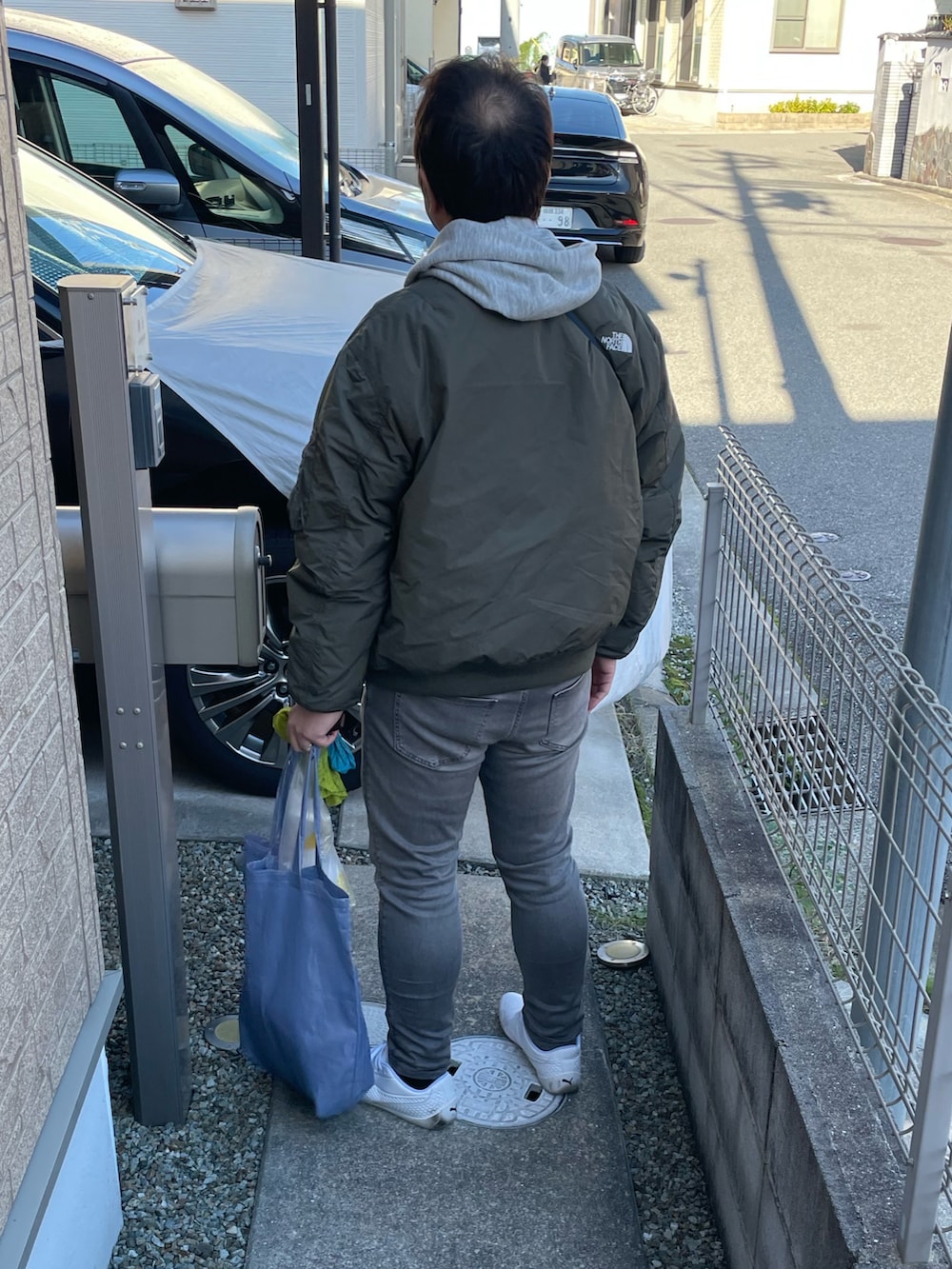 グレー系のデニムパンツ、ホワイト系のシューズ、グリーン系のMA-1を着用したメンズの冬コーディネートの2枚目の写真