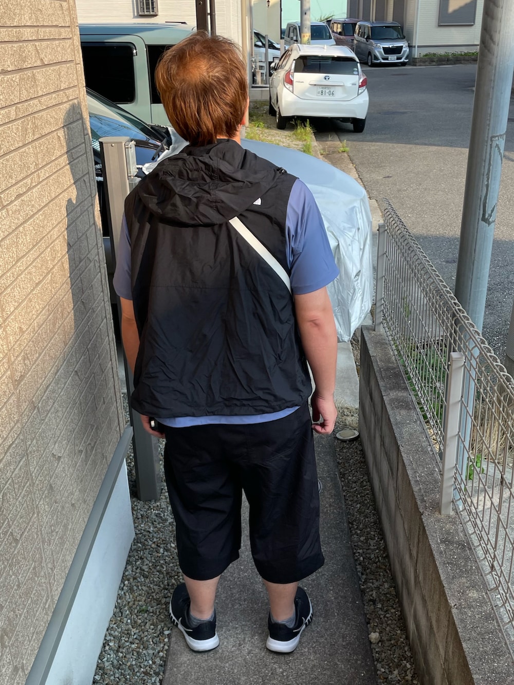 ブラック系のベスト、ブルー系のTシャツ/カットソー、ホワイト系のショルダーバッグを着用したメンズの夏コーディネートの2枚目の写真