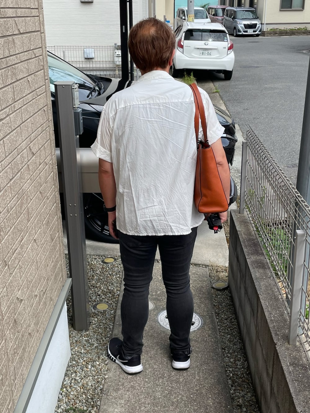 ホワイト系のシャツ/ブラウス、オレンジ系のトートバッグ、グレー系のデニムパンツを着用したメンズの夏コーディネートの2枚目の写真