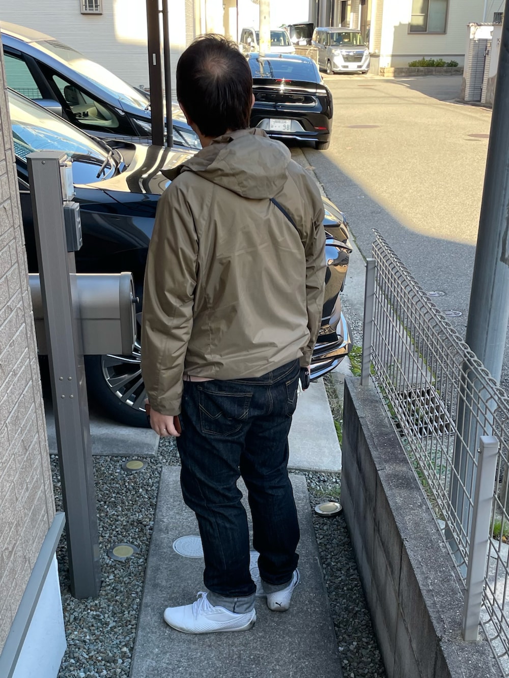 ベージュ系のマウンテンパーカー、ブルー系のショルダーバッグ、ブラック系のデニムパンツを着用したメンズの秋コーディネートの2枚目の写真