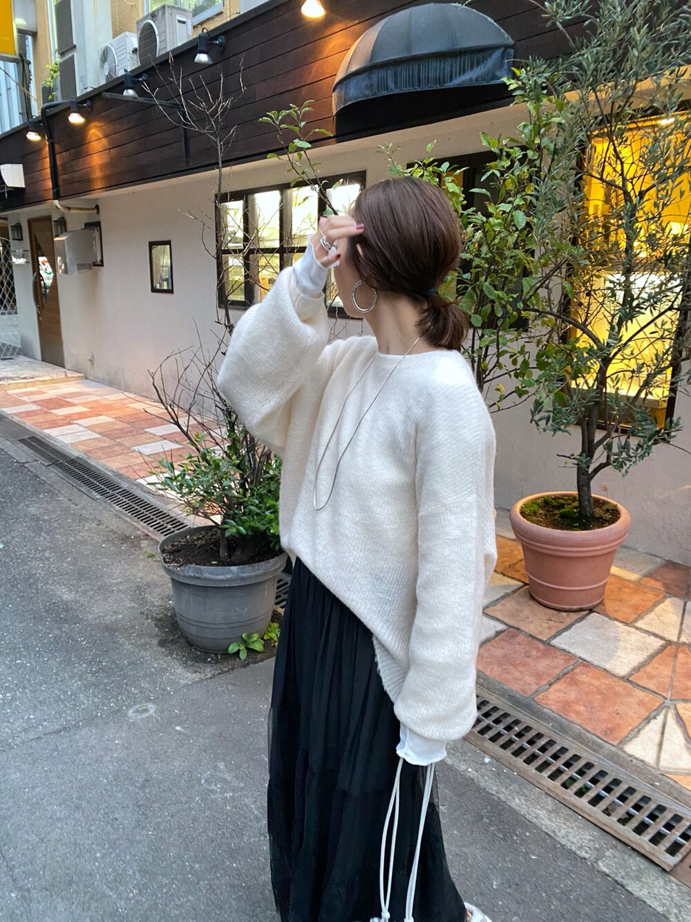 ピンク系のニット/セーター、シルバー系のハンドバッグを着用したレディースの秋コーディネートの2枚目の写真