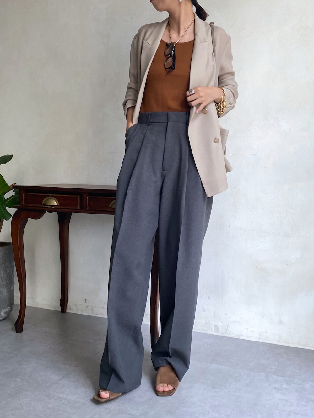 ベージュ系のテーラードジャケット、ブラウン系のタンクトップ、グレー系のパンツを着用したレディースの夏コーディネートの2枚目の写真