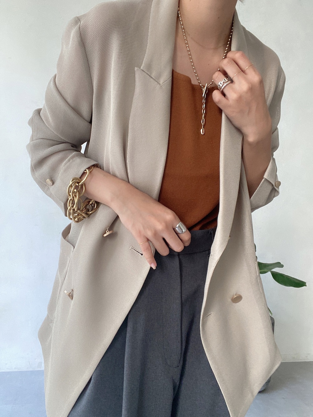 ベージュ系のテーラードジャケット、ブラウン系のタンクトップ、グレー系のパンツを着用したレディースの夏コーディネートの3枚目の写真