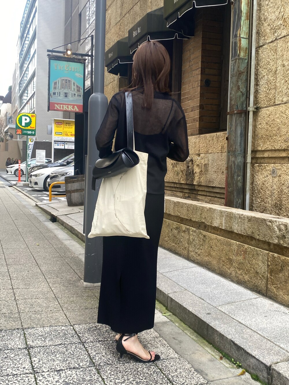 ブラック系のニット/セーター、ブラック系のスカートを着用したレディースの春コーディネートの2枚目の写真