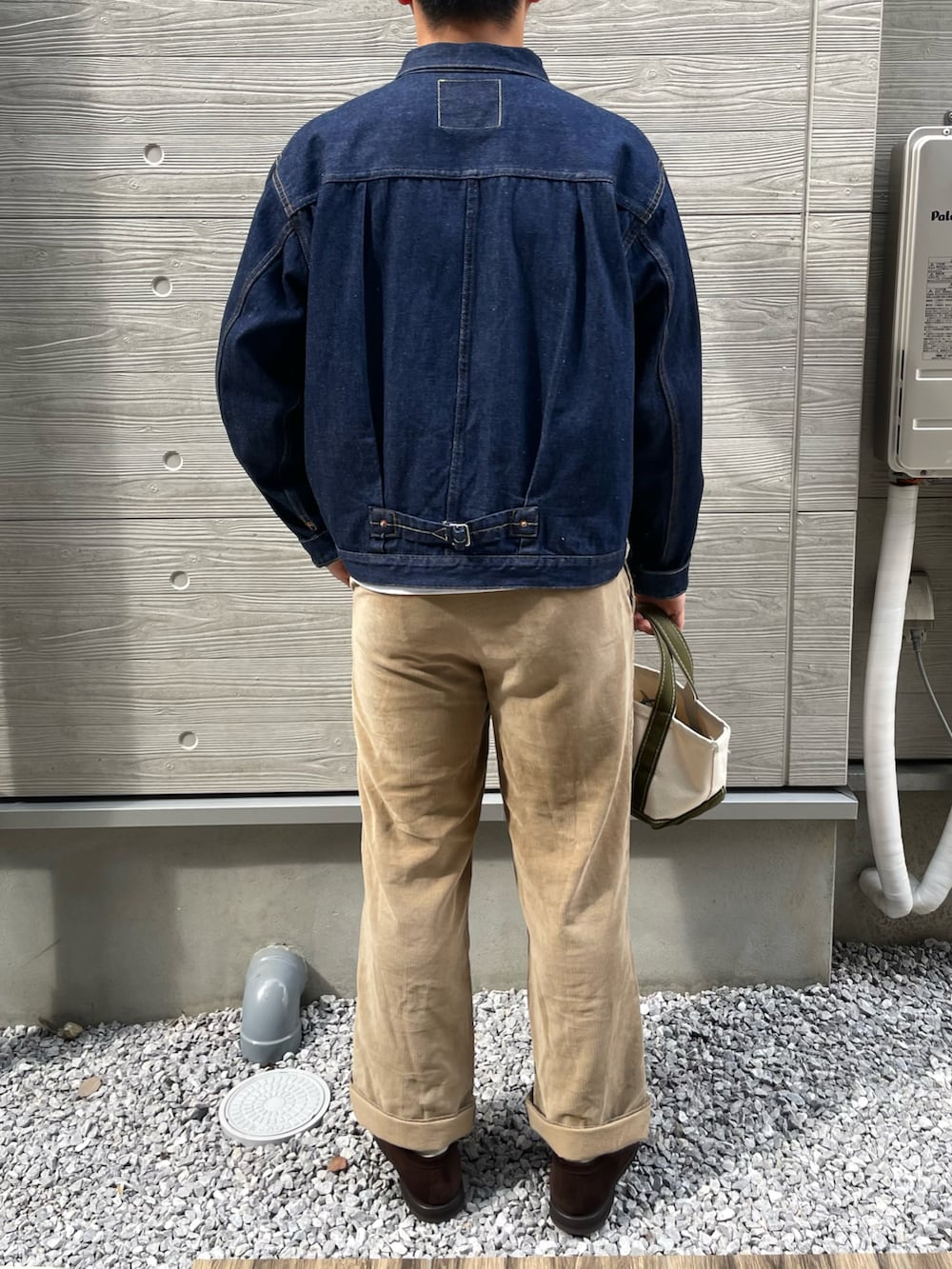 ブルー系のデニムジャケット、ベージュ系のパンツ、ブラウン系のローファーを着用したメンズの秋コーディネートの2枚目の写真
