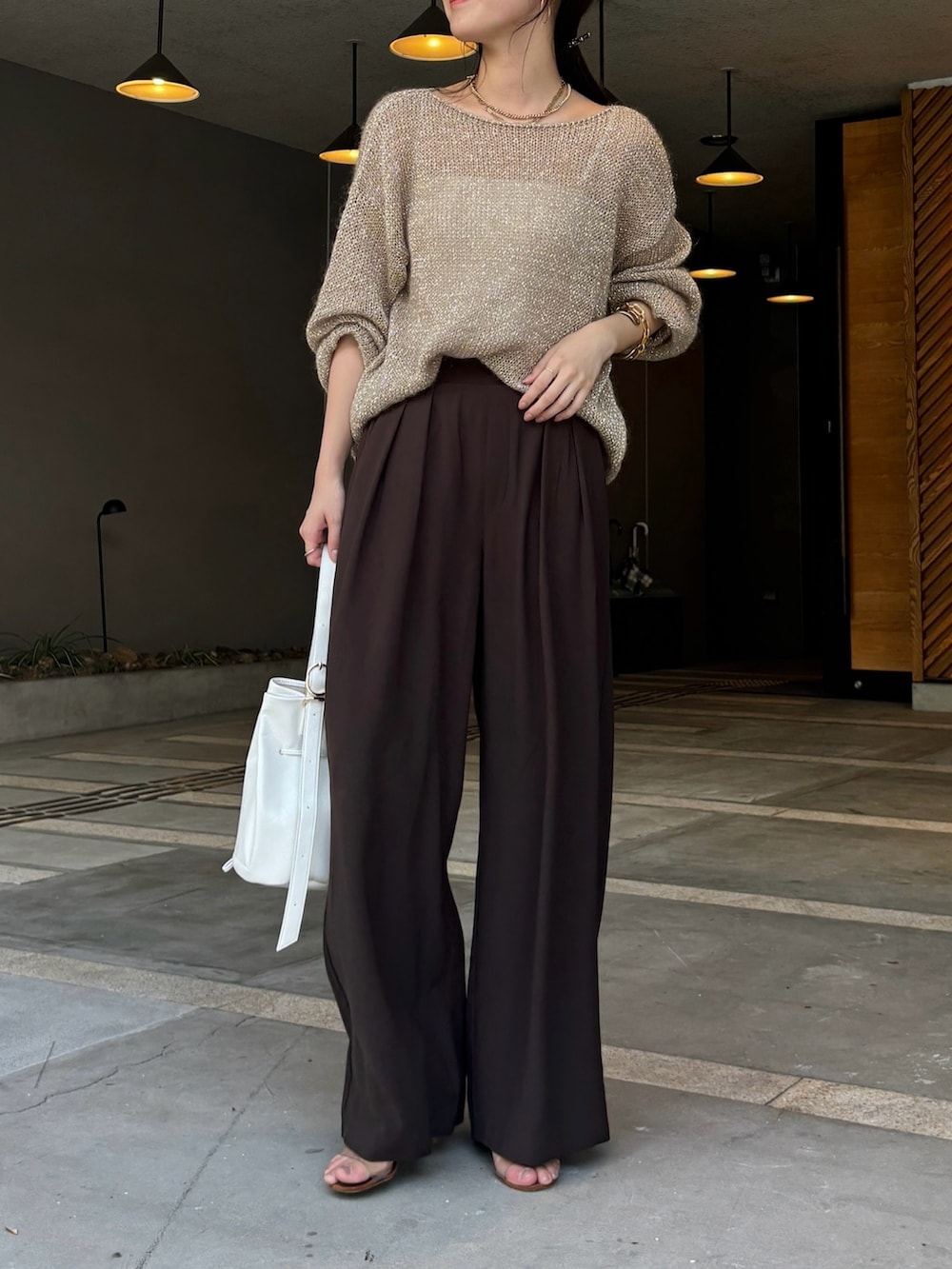 ブラウン系のスラックス、ベージュ系のニット/セーター、ホワイト系のショルダーバッグを着用したレディースの夏コーディネートの4枚目の写真