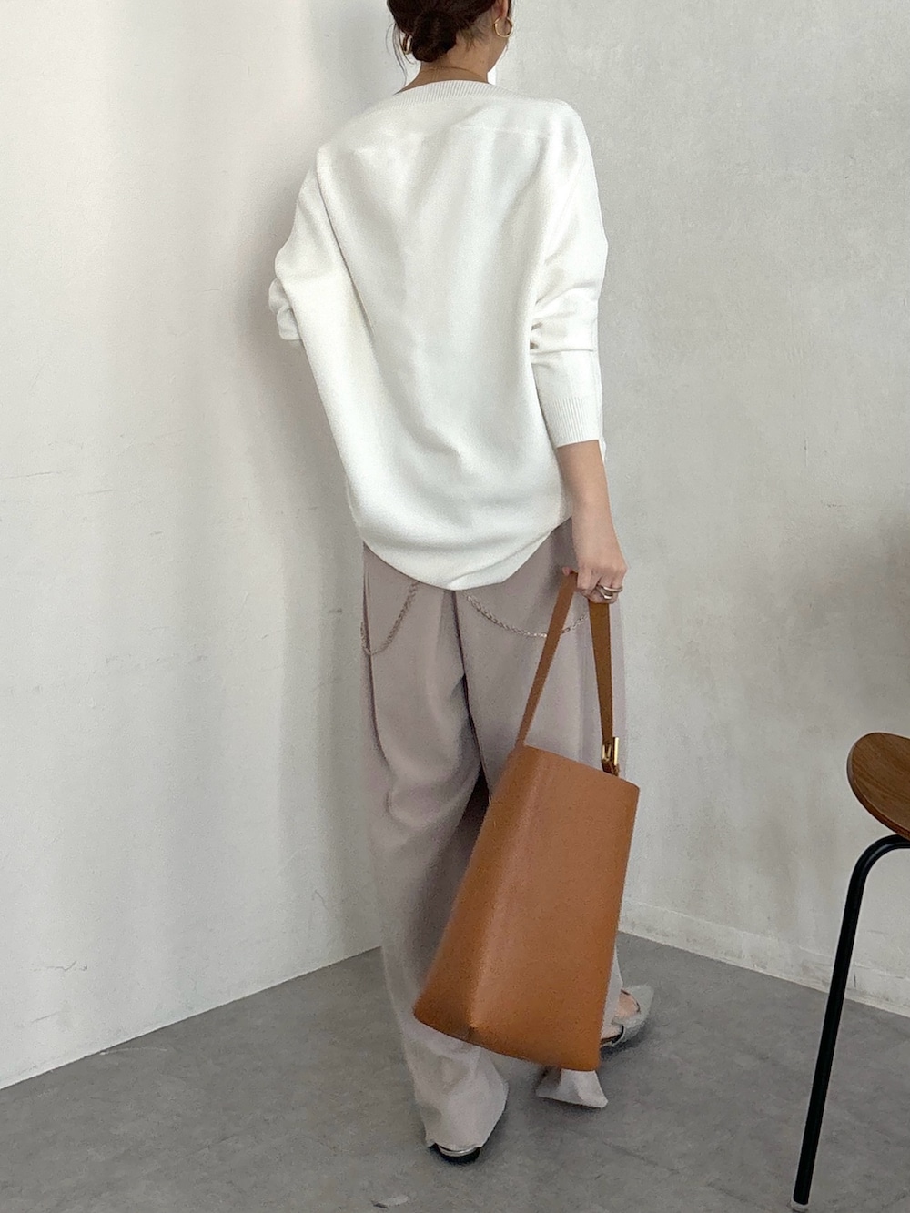 イエロー系のショルダーバッグ、ベージュ系のスラックス、ゴールド系のブレスレットを着用したレディースの冬コーディネートの6枚目の写真