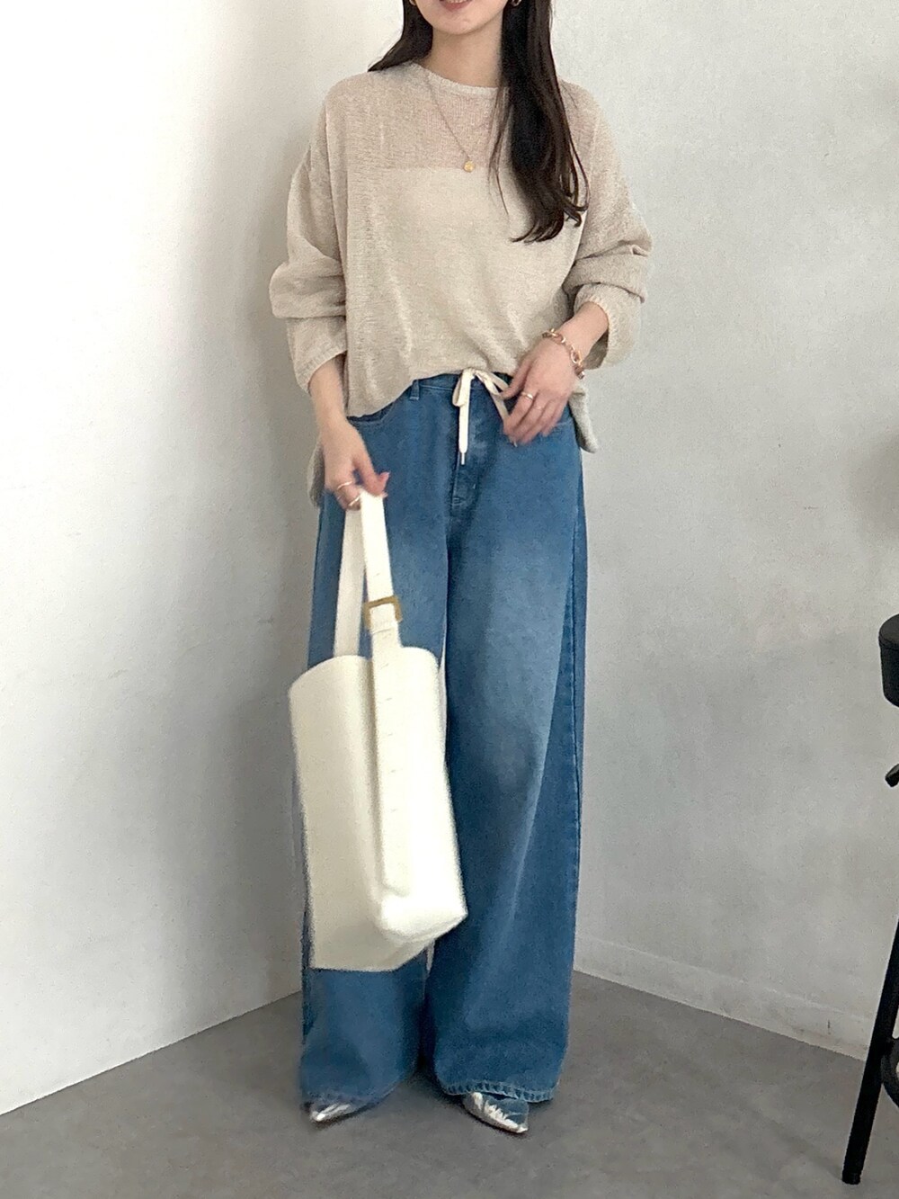 ベージュ系のニット/セーター、ホワイト系のショルダーバッグ、ブルー系のデニムパンツを着用したレディースの春コーディネートの4枚目の写真