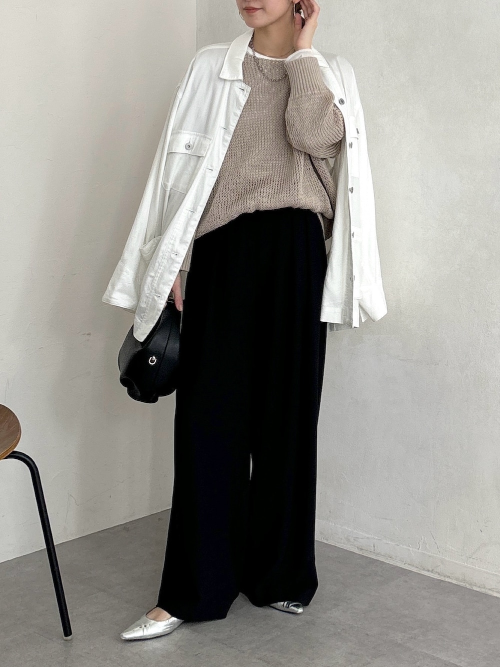 ブラック系のスラックス、ベージュ系のニット/セーター、ホワイト系のTシャツ/カットソーを着用したレディースの春コーディネートの4枚目の写真