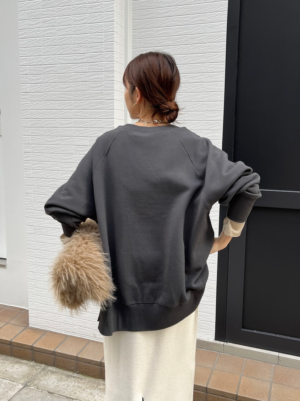 グレー系のTシャツ/カットソー、ホワイト系のスカート、ブラック系のブーツを着用したレディースの冬コーディネートの7枚目の写真